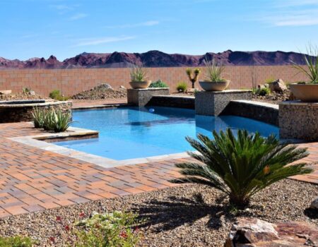 A pool with a brick patio and a desert landscape.